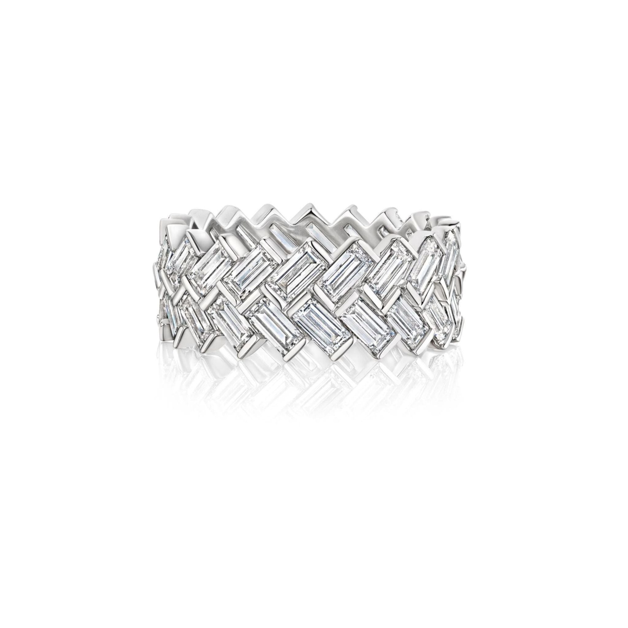 A wide, silver ring with a woven pattern, featuring rectangular clear gemstones set in a zigzag design, displayed on a white background with a soft reflection below.
