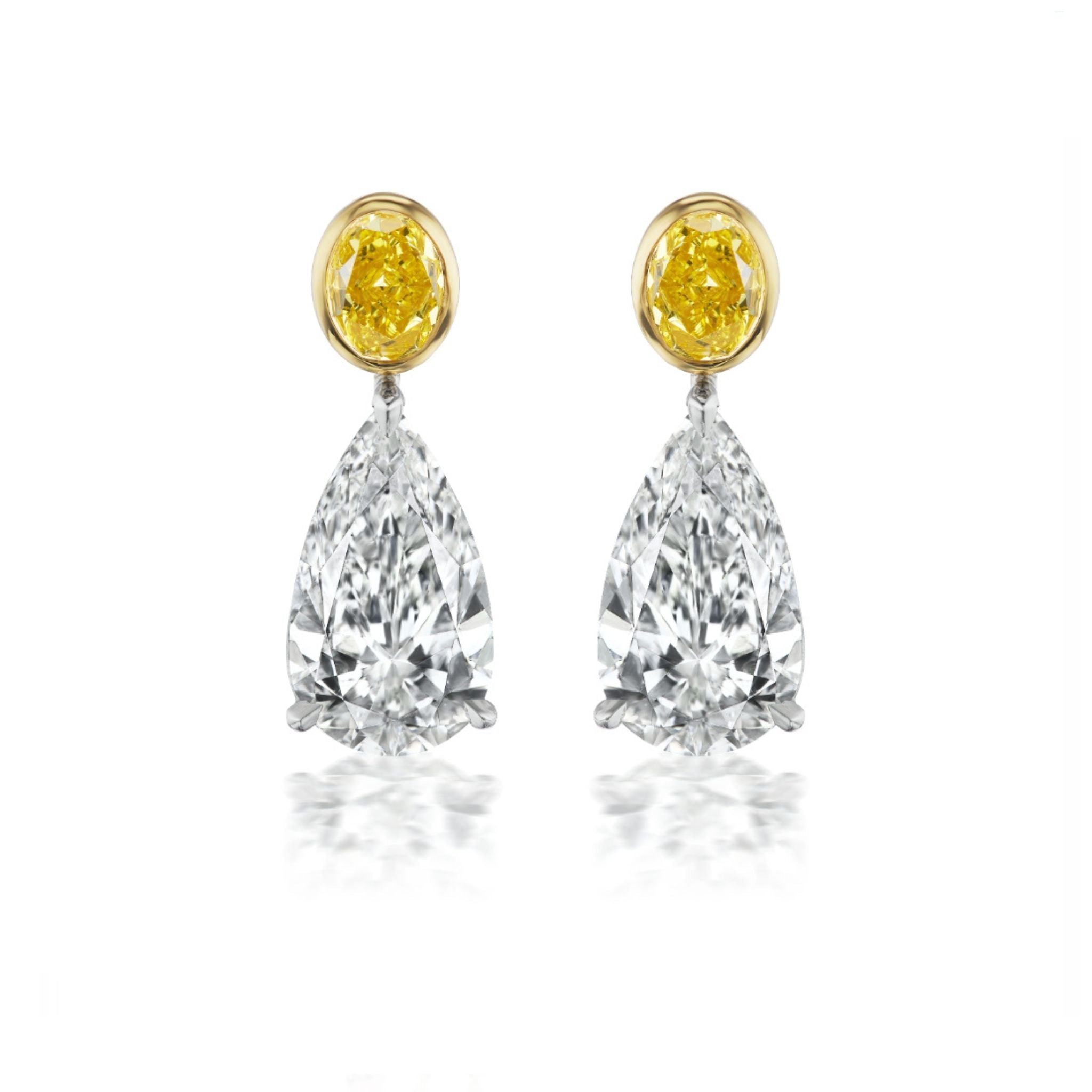 A pair of earrings with round yellow gemstones at the top and large pear-shaped clear diamonds hanging below, set in a minimalist metal setting.