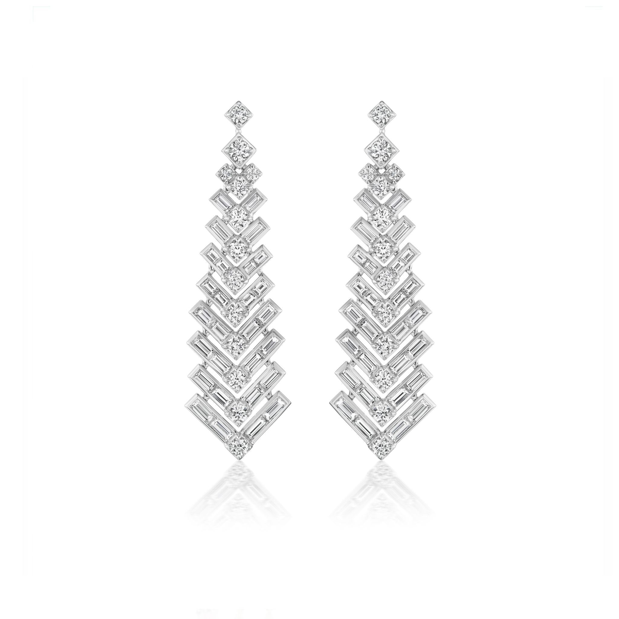 Pair of long, silver, geometric drop earrings with stacked diamond shapes and intricate zigzag patterns, featuring sparkling gemstones arranged in a cascading design.