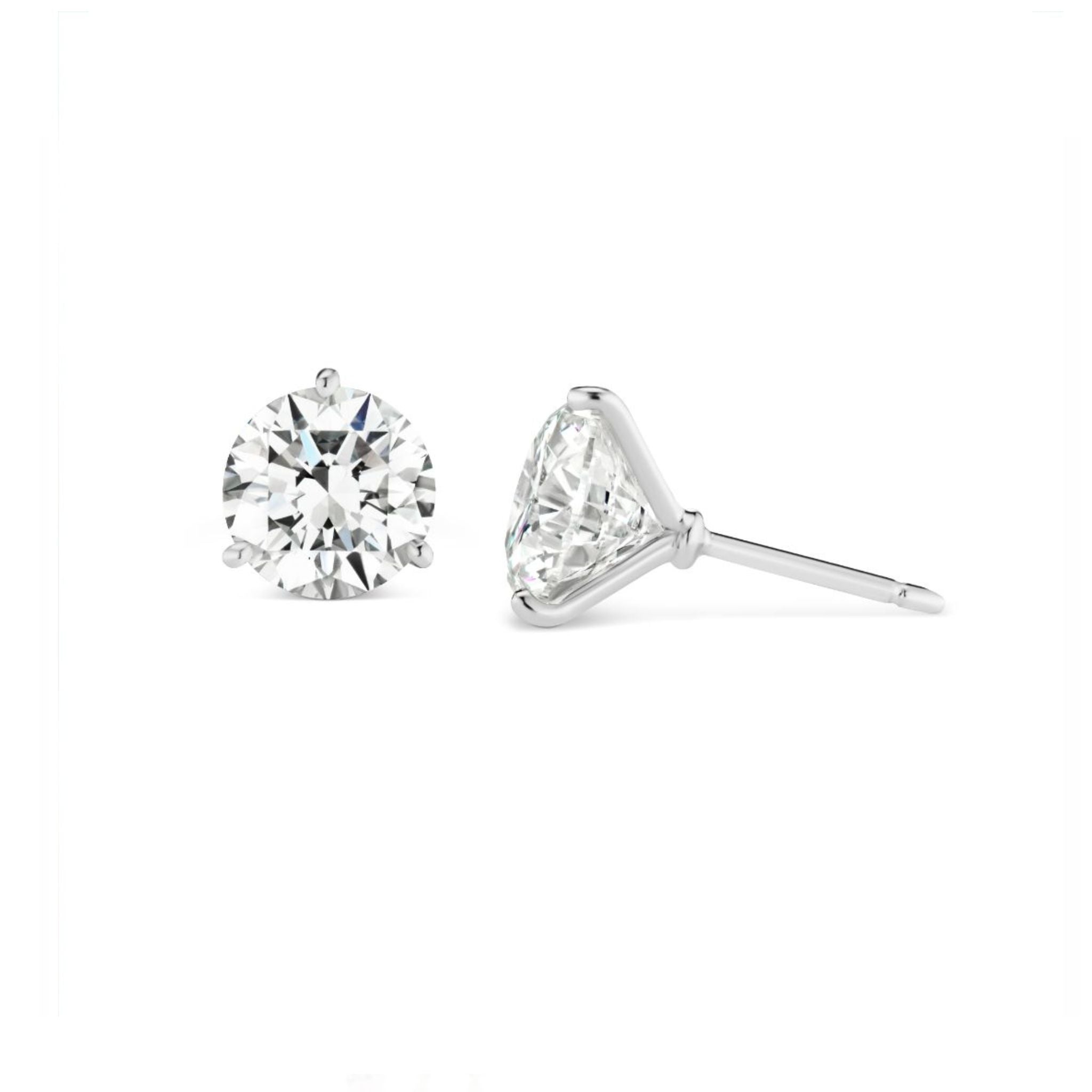 A pair of round diamond stud earrings with silver prong settings; one earring is shown from the front and the other from the side on a white background.