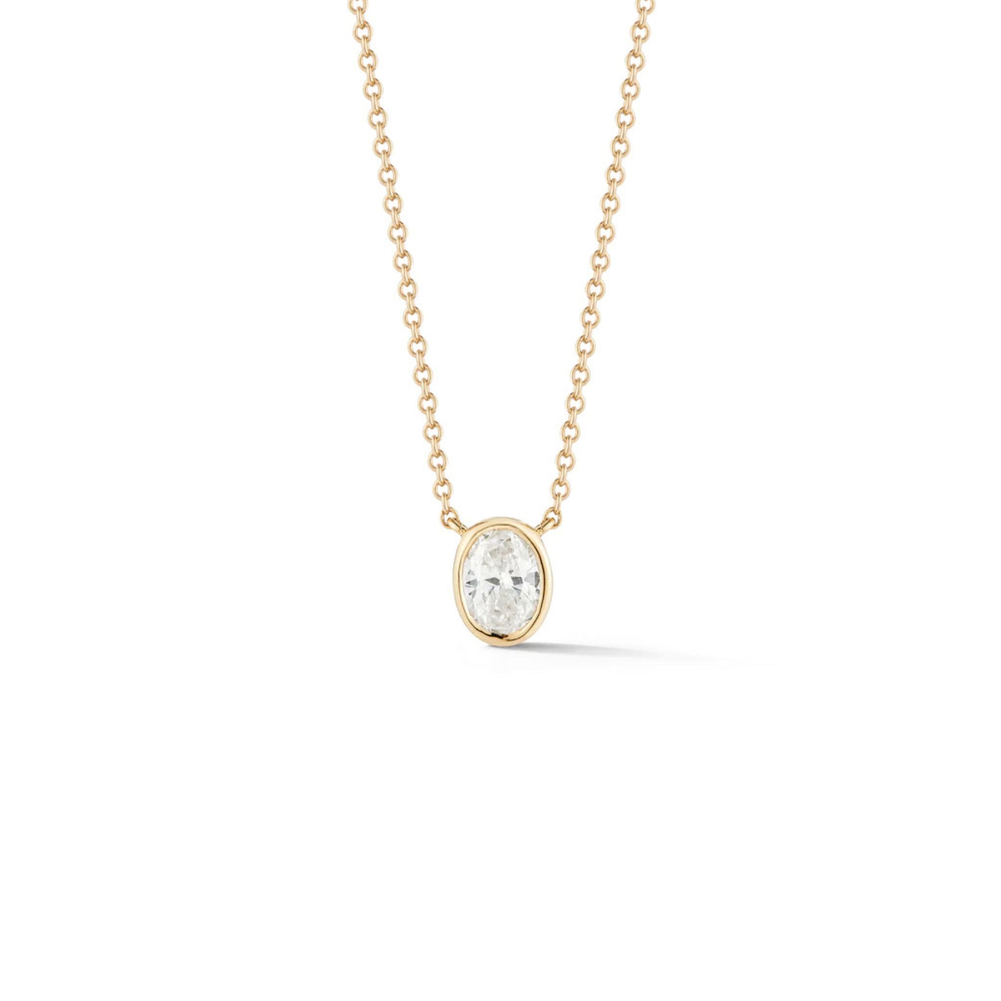 A delicate gold chain necklace featuring a single pear-shaped clear gemstone set in a simple gold bezel, displayed against a plain white background.