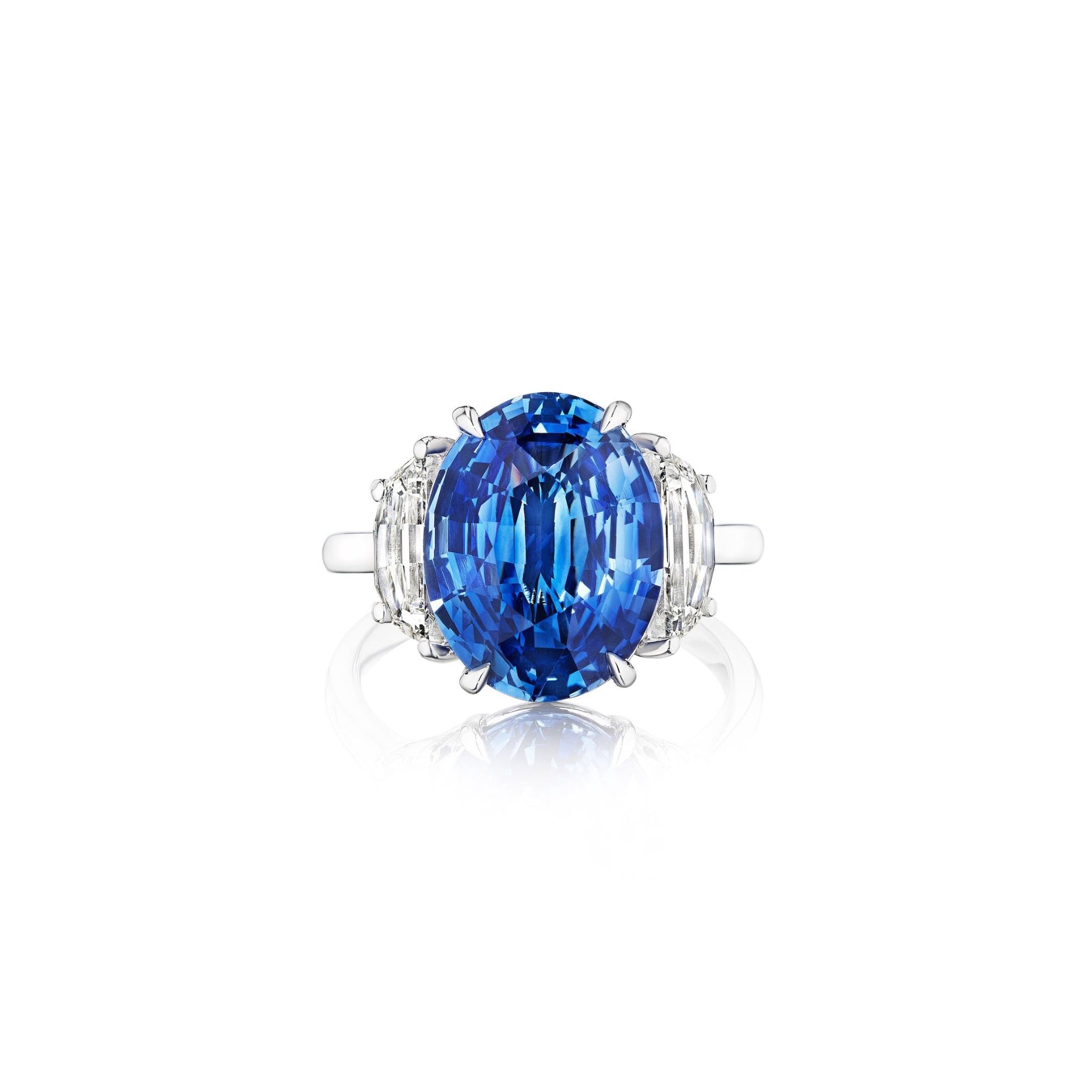 A silver ring featuring a large oval blue gemstone at the center, flanked by two clear baguette-cut side stones, displayed on a white background.