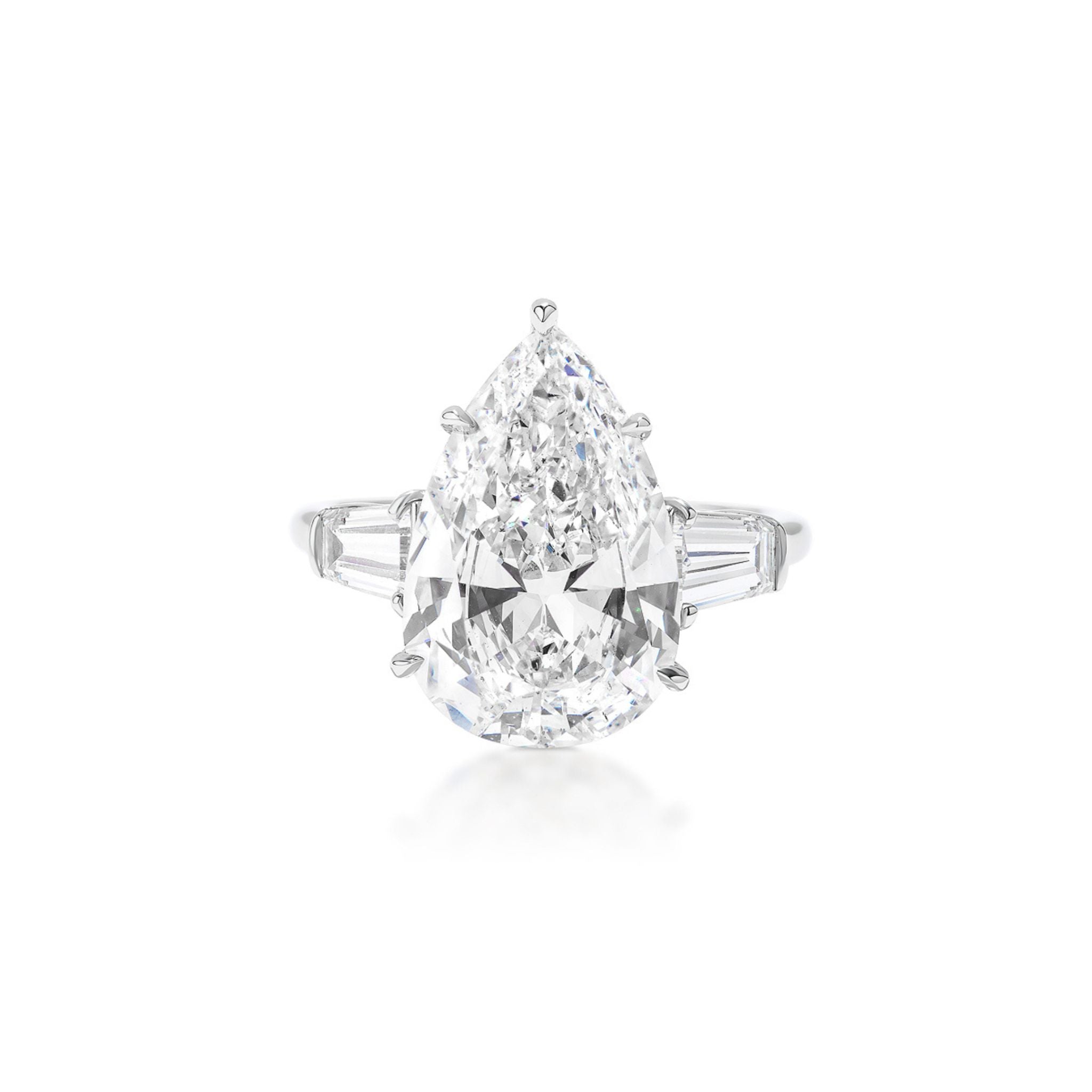 A pear-shaped diamond ring with a large central diamond flanked by tapered baguette-cut diamonds on a simple metal band, displayed against a white background.