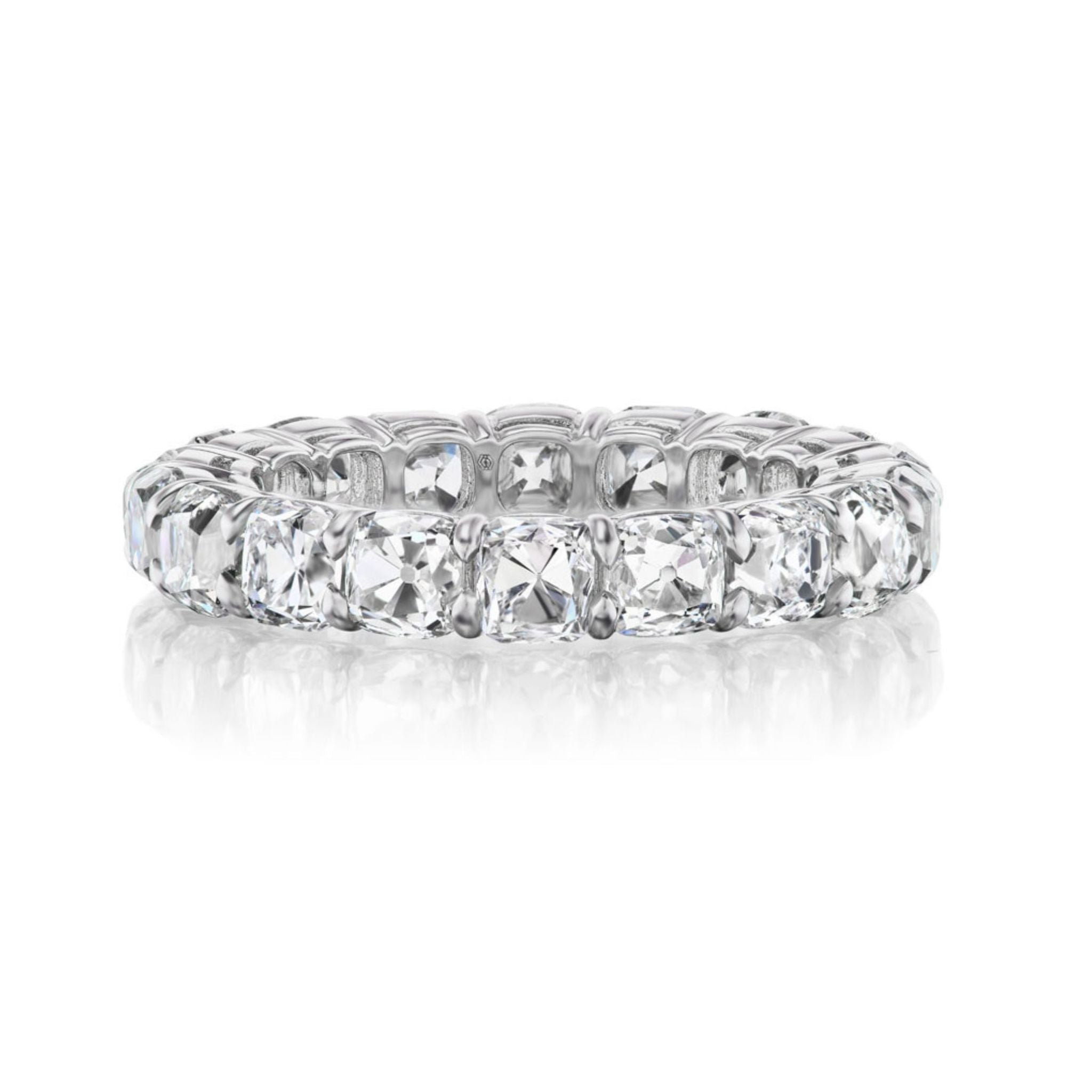 A silver eternity band ring set with large cushion-cut clear gemstones all around, displayed against a white background with a subtle reflection below.