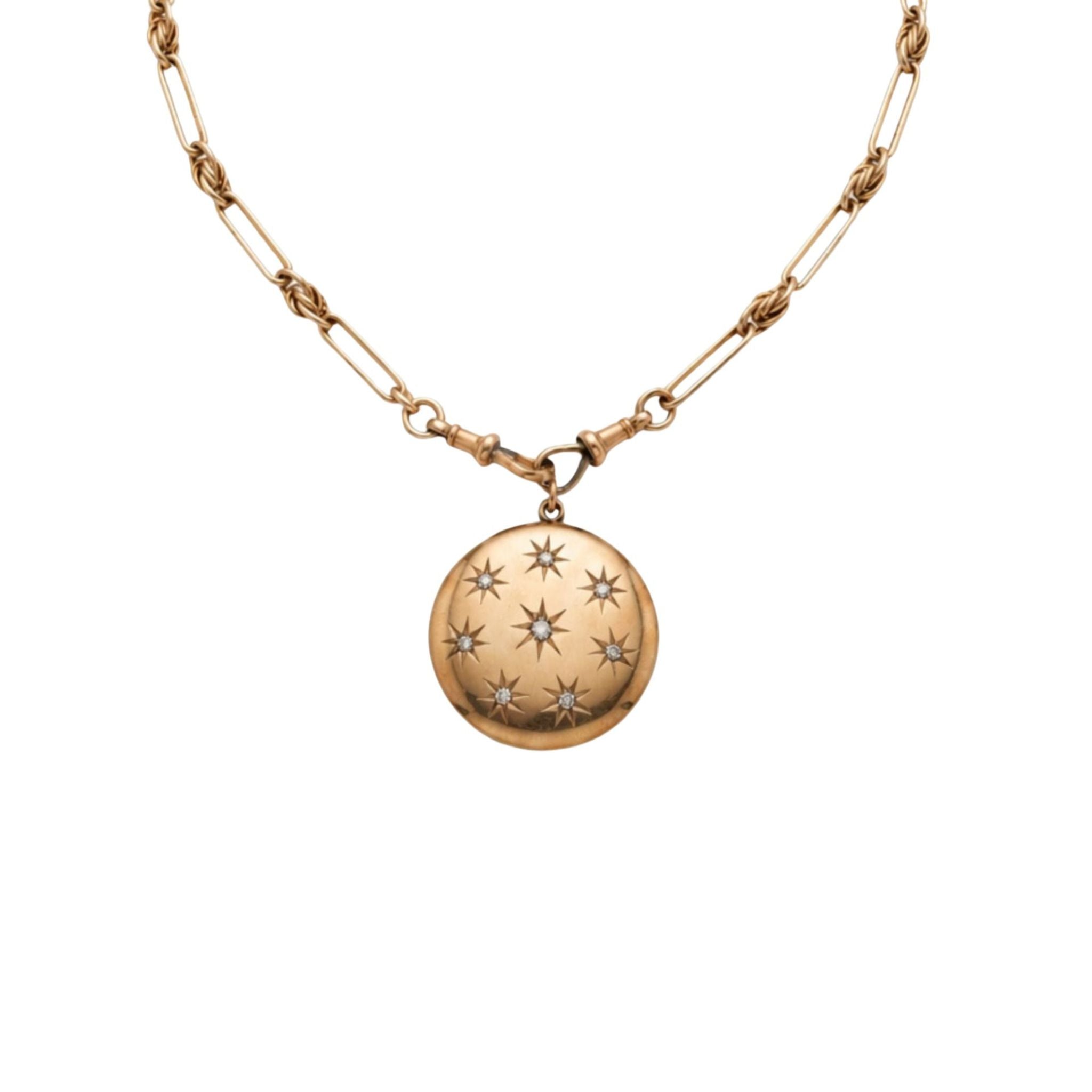 A gold chain necklace with a round gold locket pendant, decorated with a pattern of engraved stars on its surface, displayed against a white background.