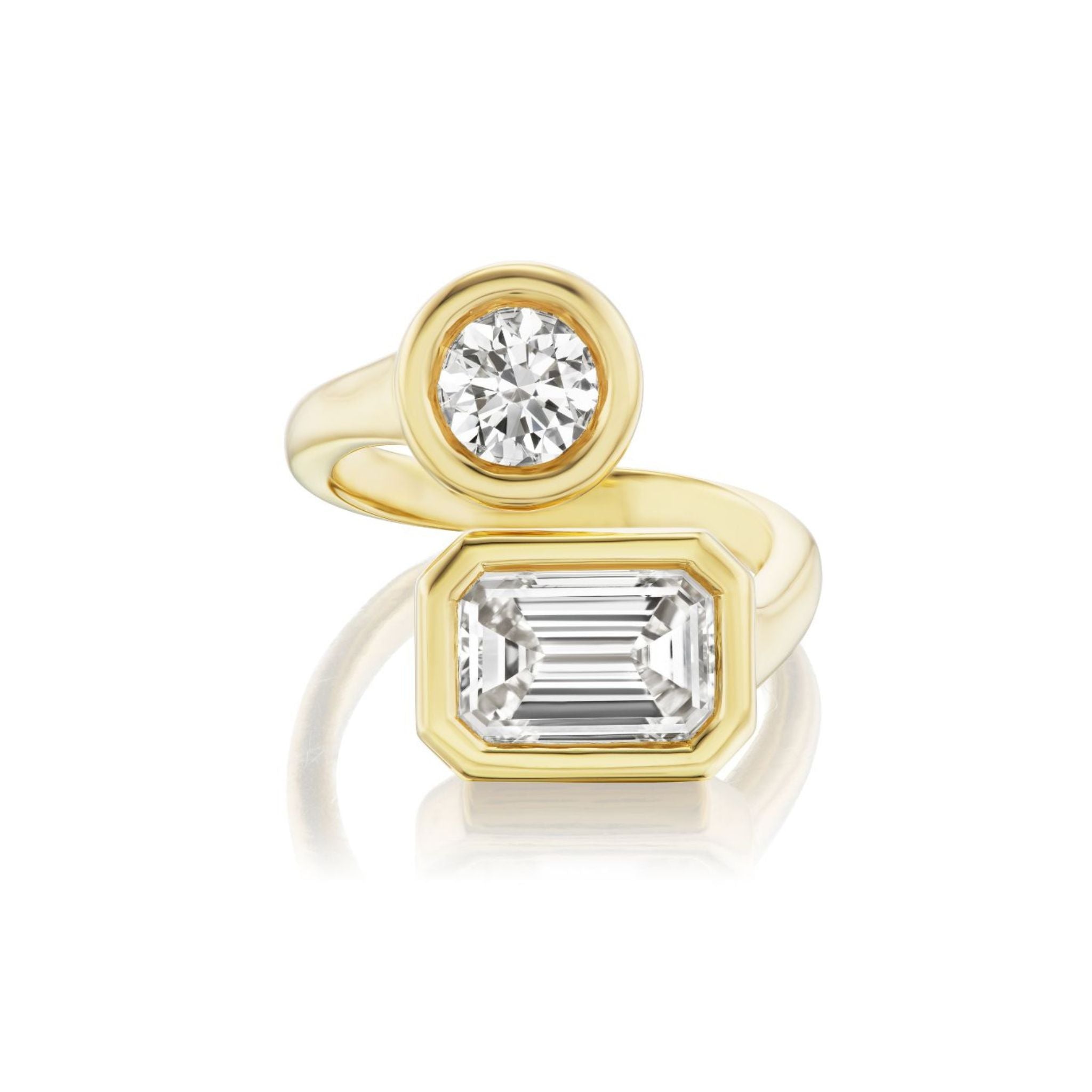 A gold ring with two diamonds: one round-cut diamond set in a circular bezel and one emerald-cut diamond set in an octagonal bezel, both on a polished gold band.