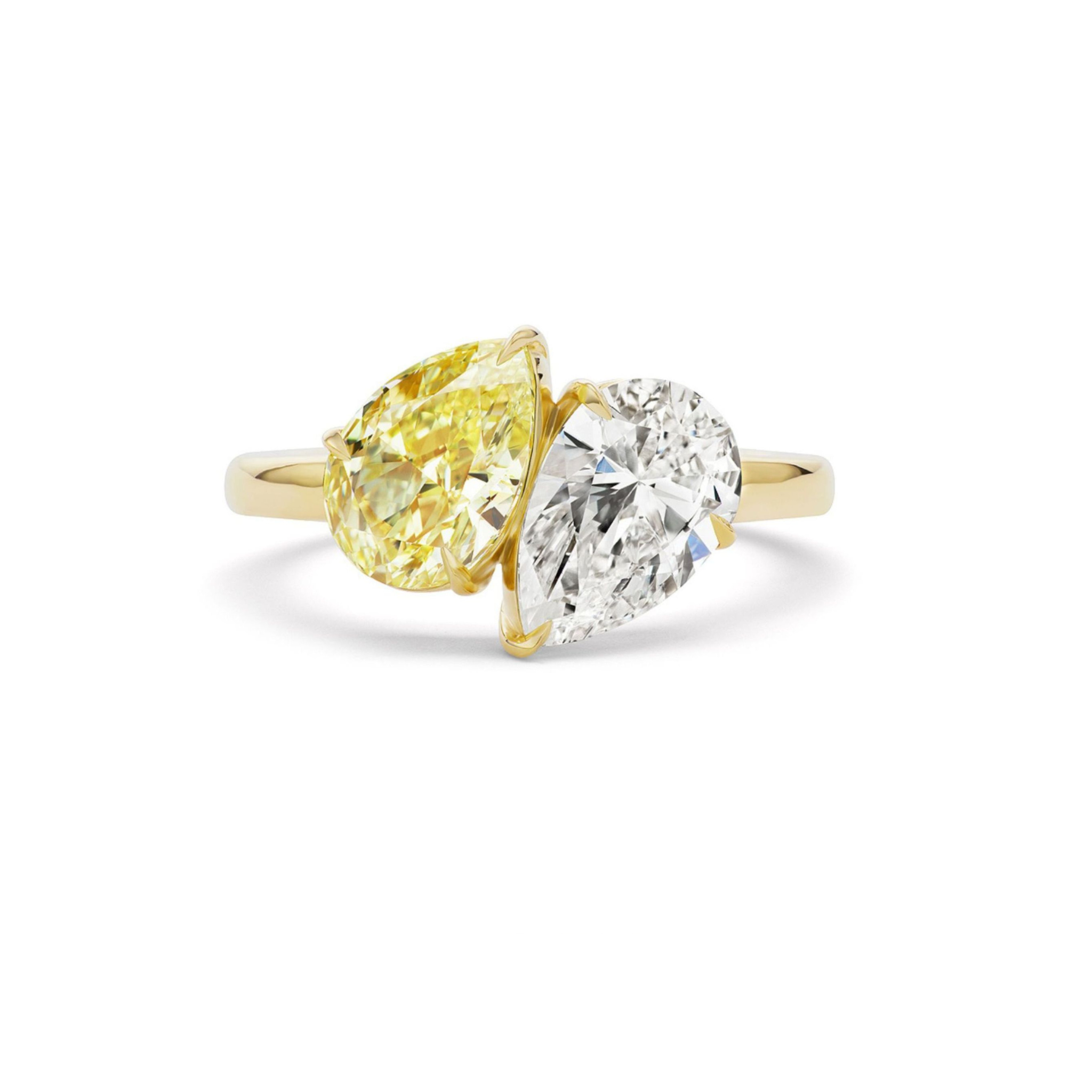 A gold ring featuring a large pear-shaped yellow diamond and a rectangular emerald-cut clear diamond set side by side in elegant prongs.