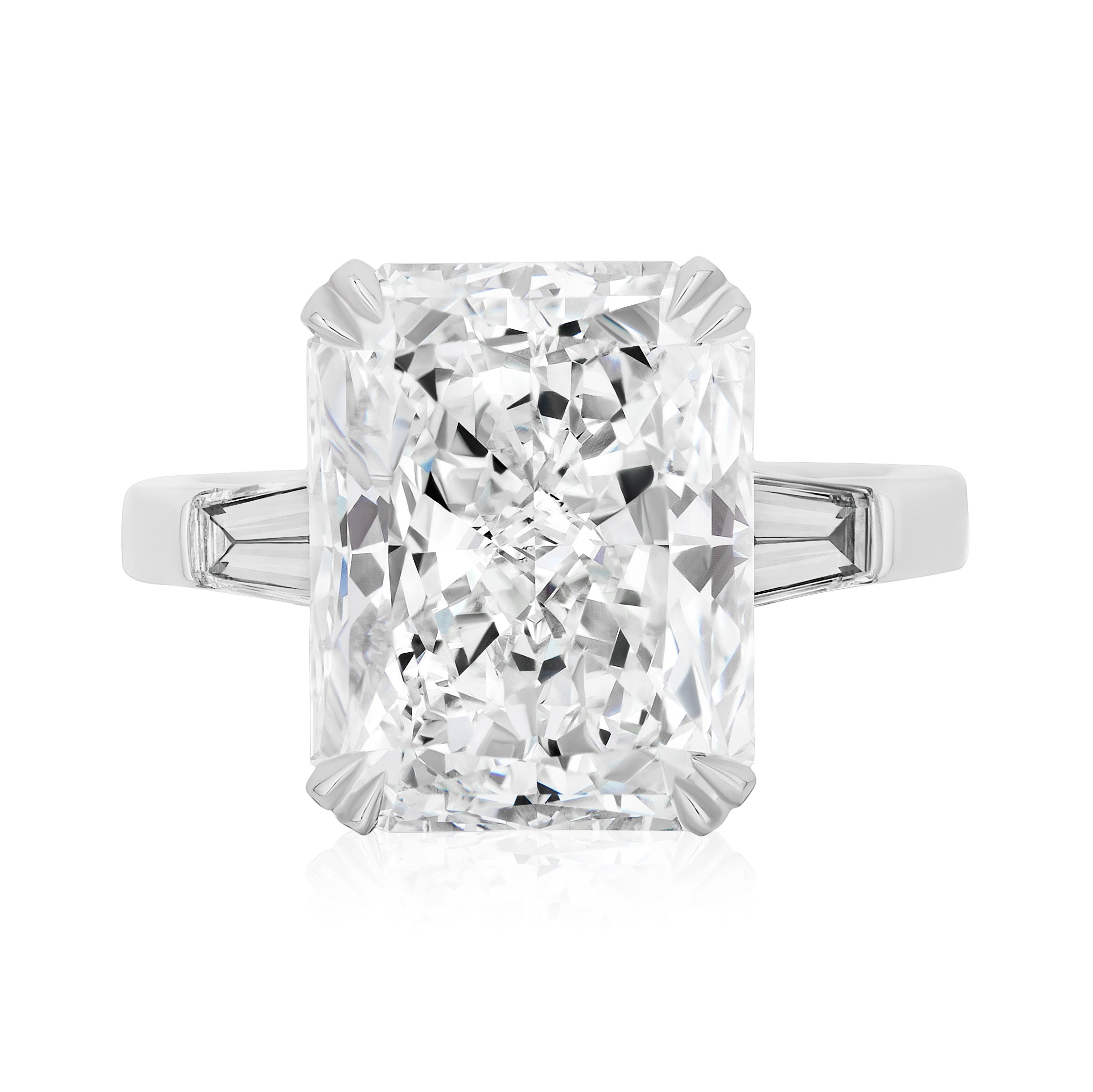 The Radiant Cut Diamond Engagement Ring with Tapered Baguettes features a rectangular center diamond and tapered baguette side stones on a white metal band, making it an elegant celebration ring shown against a white background.