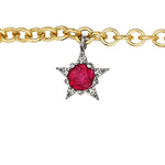The America250 Ruby, Pearl, Sapphire, and Diamond Charm Bracelet in yellow gold features an 18k gold chain with a star-shaped pendant adorned with a large red gemstone and clear stones on silver-colored points.
