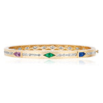 The Bezel Set Mixed Shape Sapphire, Emerald, and Baguette Diamond Bangle showcases a central emerald, pink gemstone, blue sapphires, and rows of sparkling baguette diamonds in an 18k yellow gold design.