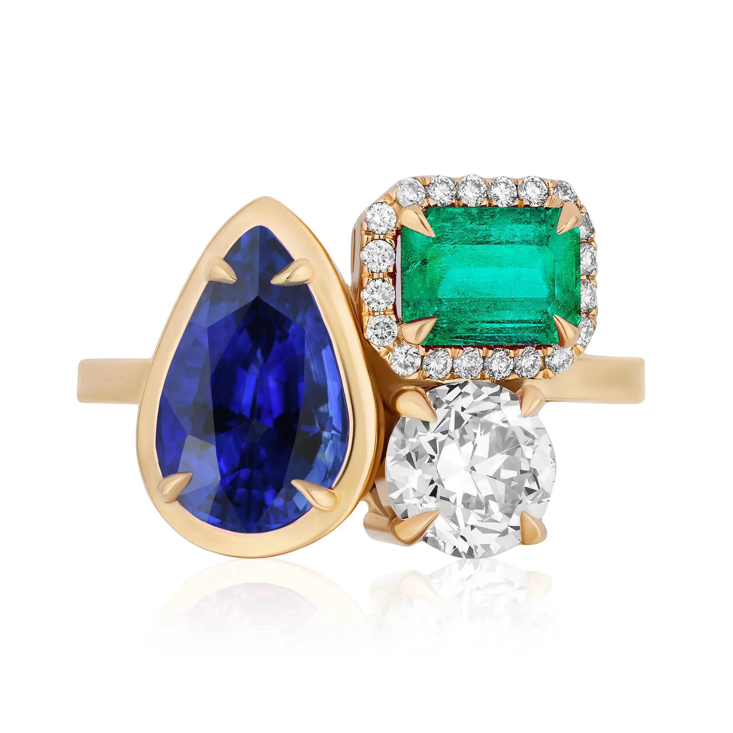 The Cluster Ring in yellow gold features a collet set pear shape sapphire, pavé emerald cut emerald, and round diamond set closely together.