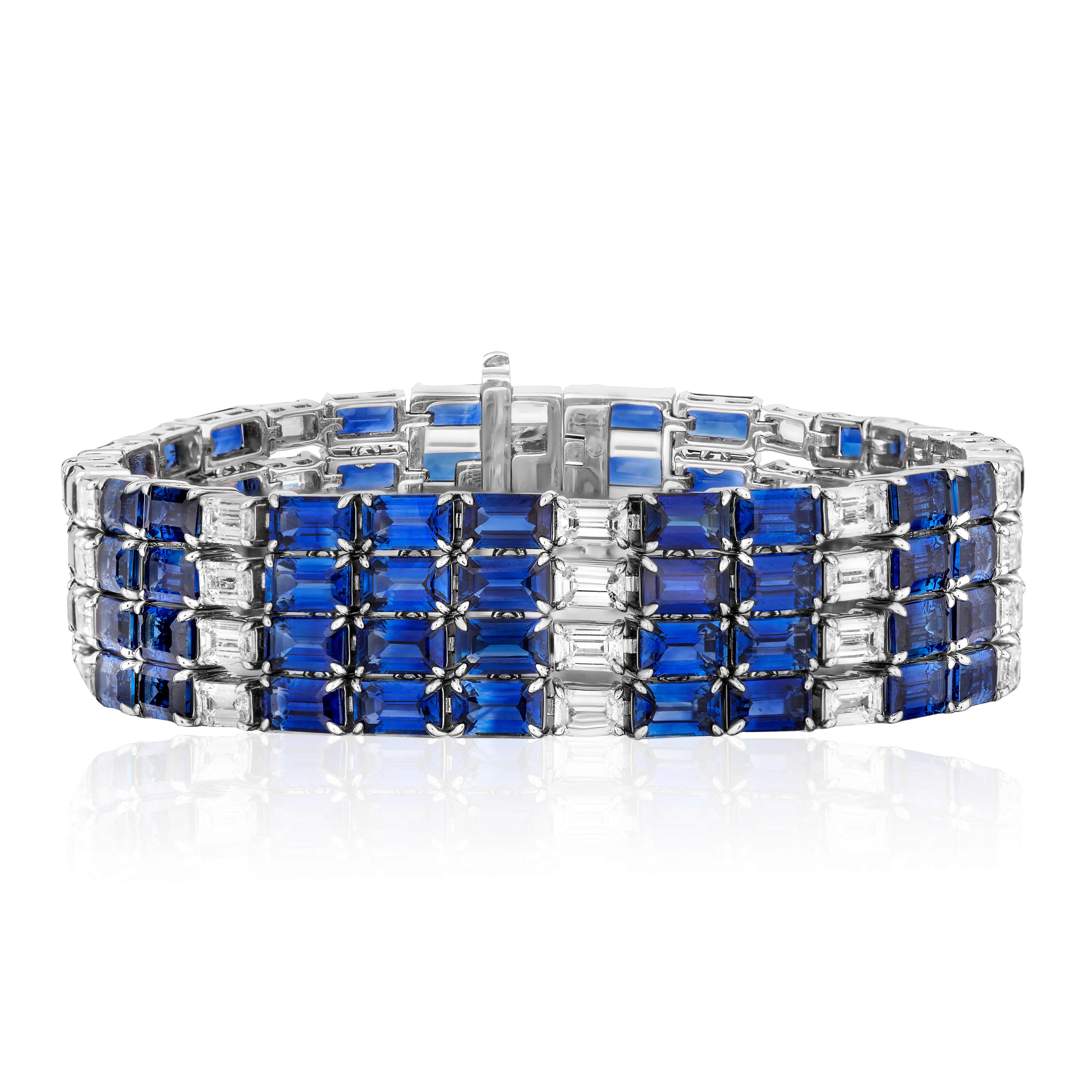 The Multi Strand Sapphire and Diamond Tennis Bracelet in white gold features alternating rows of emerald cut sapphires and clear diamonds set in a geometric pattern for a luxurious look.