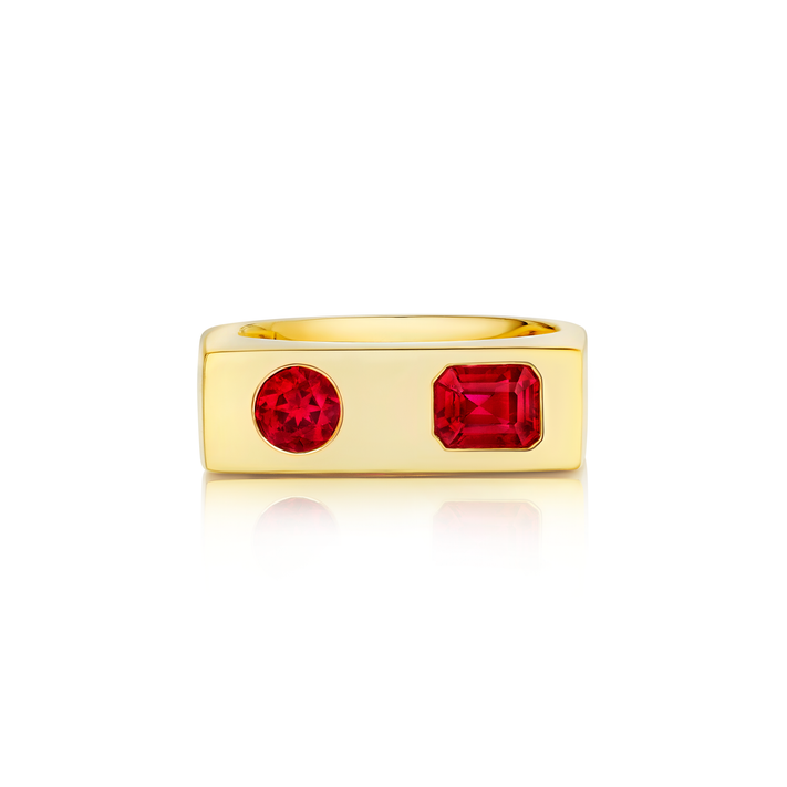 The Bar Ring with Round and Emerald Cut Rubies in Yellow Gold features a flat rectangular band with two vibrant rubies—one round, one emerald cut—set side by side on top.