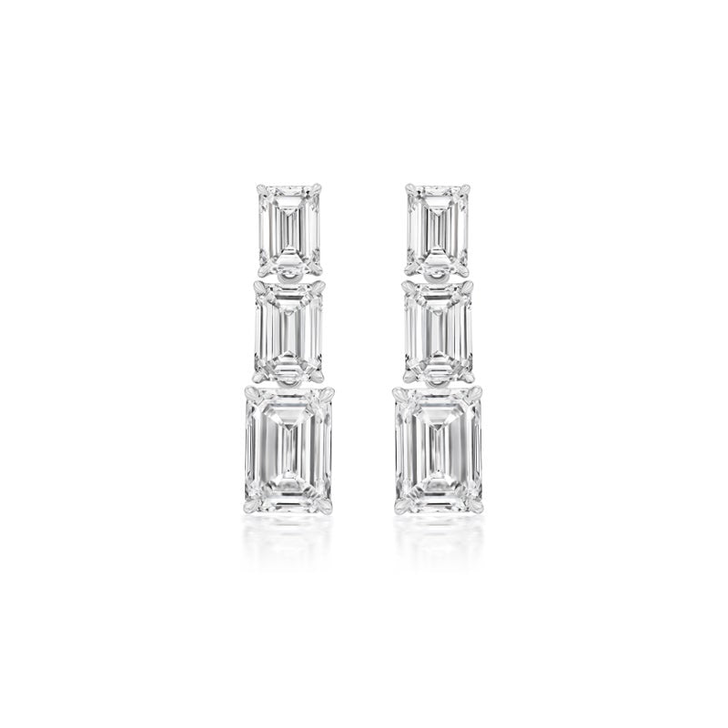 Graduated Emerald Cut Diamond Drop Earrings in White Gold feature three stacked rectangular diamonds per earring, elegantly set in a row. GIA certified and displayed on a plain white background.
