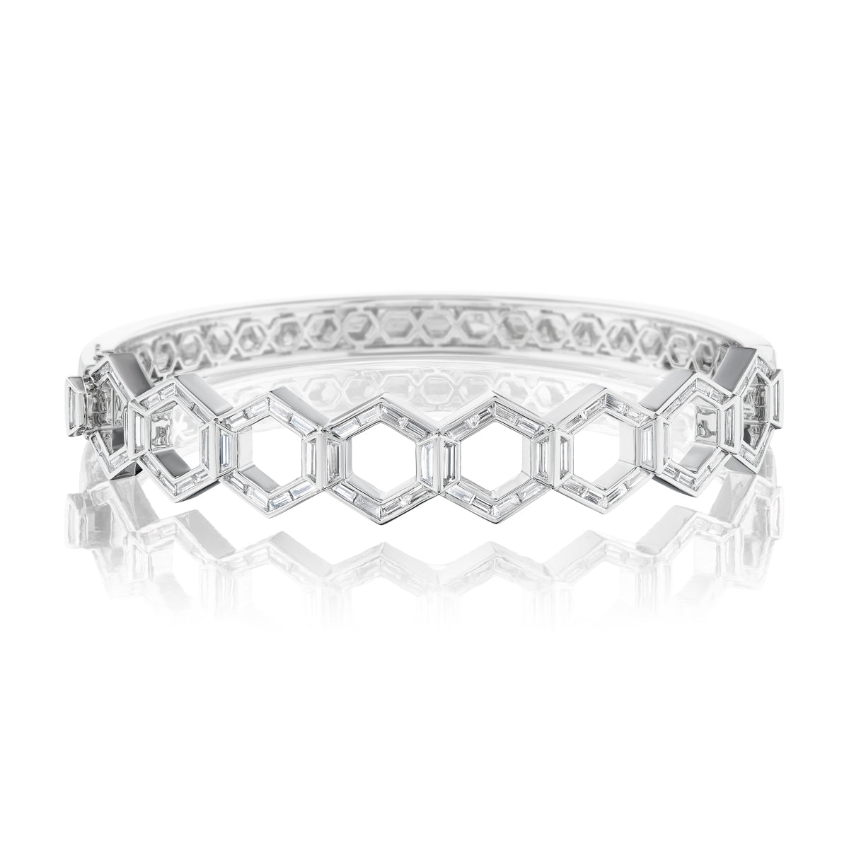 A Chrysler Hexagon Bangle with Baguette Diamonds featuring a geometric design of interconnected hexagonal shapes, showcased on a reflective white surface.