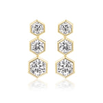 The Graduated Hexagon Bezel Set Drop Earrings feature 18K yellow gold with three vertically arranged round brilliant diamonds in hexagonal bezels, each stone increasing in size from top to bottom.