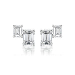 The Duo Studs in White Gold with Emerald Cut Diamonds feature two rectangular diamonds set in 18K white gold prongs, shown on a white background.