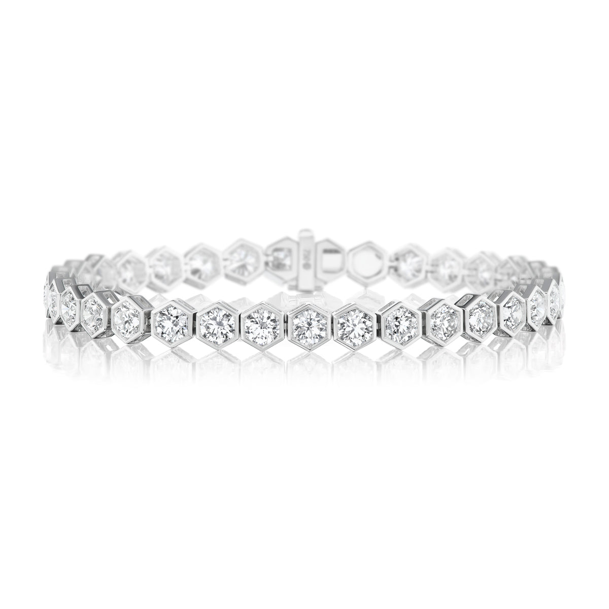 The Large Hexagon Bezel Set Diamond Tennis Bracelet, crafted in 18K gold with hexagonal links each set with a round diamond, is displayed elegantly on a white reflective surface.