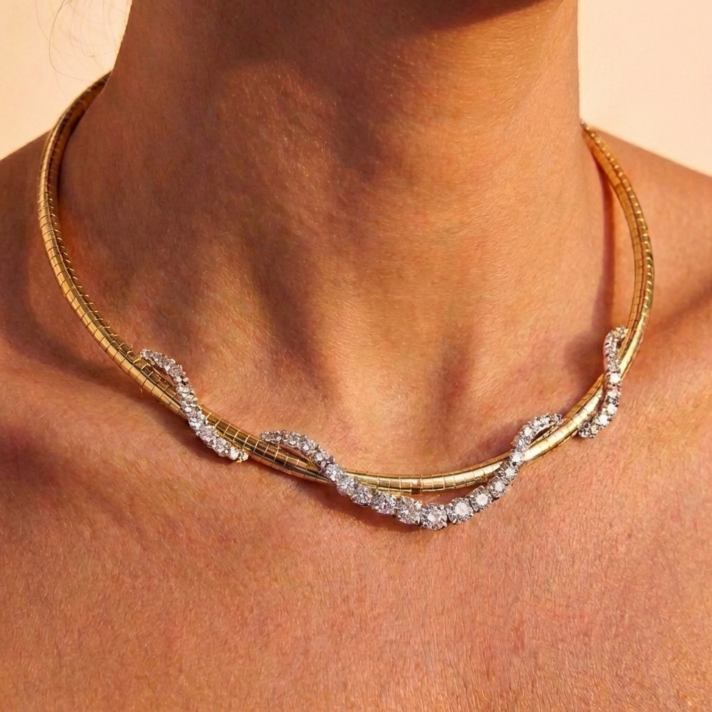 A close-up of a woman's neck wearing the Coil Graduated Round Diamond and Omega Chain Necklace in yellow gold and platinum, featuring a wavy design with sparkling round diamonds along the front.