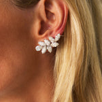 Close-up of a woman’s ear wearing the Vintage Pair of Diamond Earclips, featuring a cluster design with several marquise-shaped clear gemstones arranged in a floral or leaf pattern. Crafted in 18K white gold, these elegant earrings evoke timeless luxury, while the woman’s blonde hair partially frames the ear.