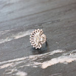 The Vintage Oscar Heyman & Brothers Diamond Ring, inspired by the refined elegance of platinum craftsmanship from 1946, showcases a distinctive sunburst design with a captivating half-moon diamond and is displayed on a textured gray marble surface, radiating timeless sophistication.