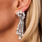 Close-up of a woman’s ear adorned with the Meister Diamond Earrings, circa 1955—an ornate pair of chandelier earrings crafted in platinum and set with multiple large diamonds in a cascading, ribbon-like design that captures the elegance of vintage jewelry. Blonde hair softly frames her ear.