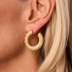 Close-up of a person’s ear adorned with a Pair of Gold and Diamond Earclips featuring a textured, star-like pattern. The wearer has light skin and blonde hair.