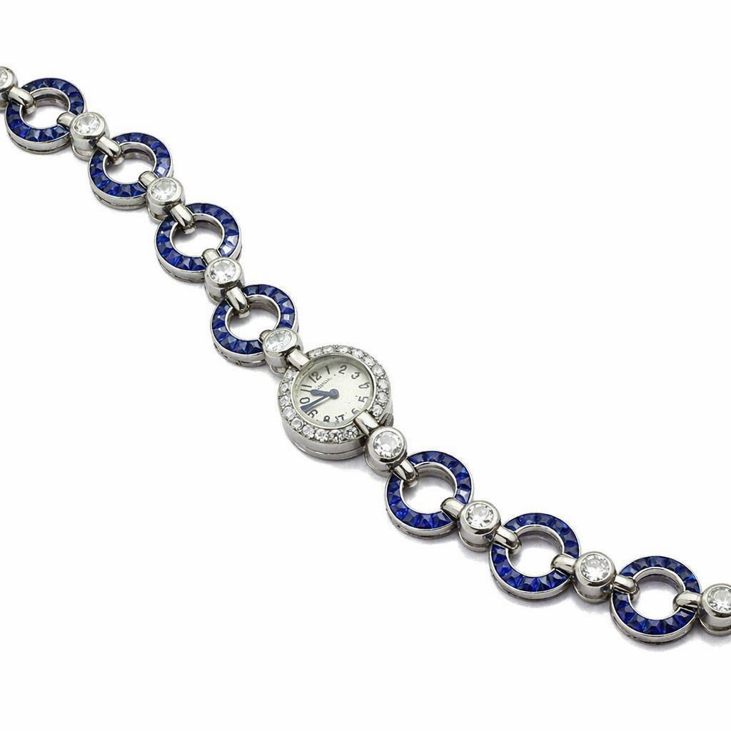 The Cartier Art Deco Sapphire and Diamond Watch features a vintage 1920s-inspired bracelet with blue and silver links, embedded diamonds, a sapphire accent, and a small round central watch face.