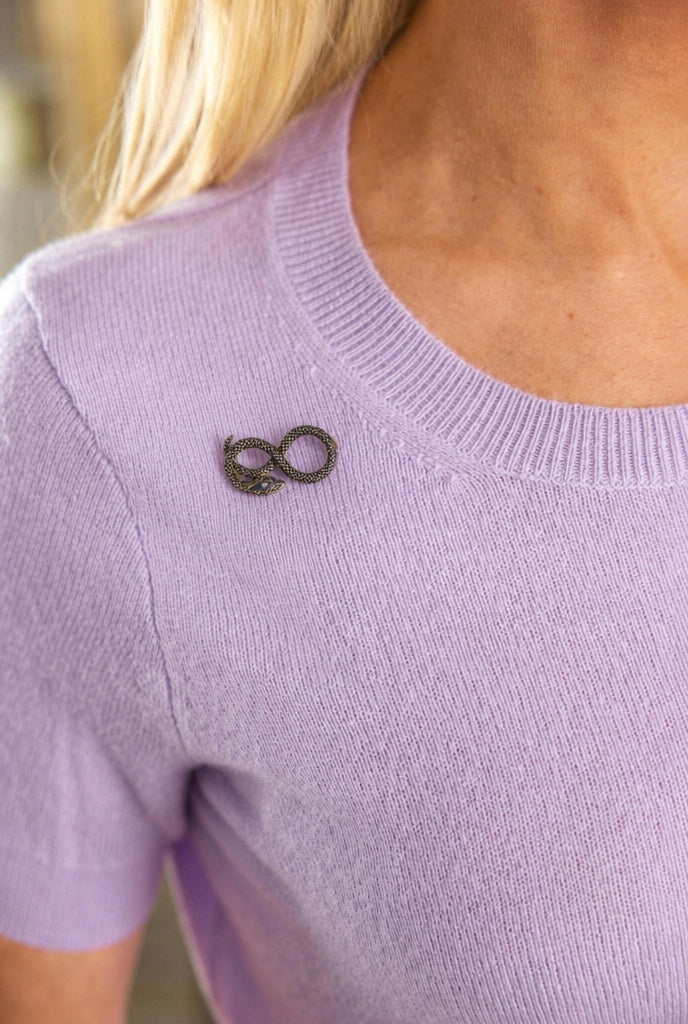 A person wears a light purple knit top with the Antique Diamond and Enamel Snake Pin near the left collar. Only their upper torso and part of their blond hair are visible.