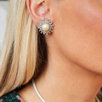 Close-up of a woman’s ear wearing Van Cleef & Arpels Pair of Pearl and Diamond Earclips. She has straight blonde hair and a silver necklace, with a blurred background.