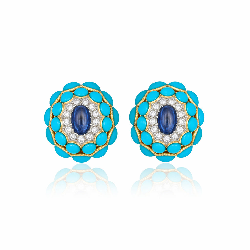 The Van Cleef & Arpels Pair of Sapphire, Turquoise and Diamond Earclips features a central blue oval sapphire, encircled by small diamonds and an outer layer of turquoise cabochons set in 18K gold, displayed on a white background.