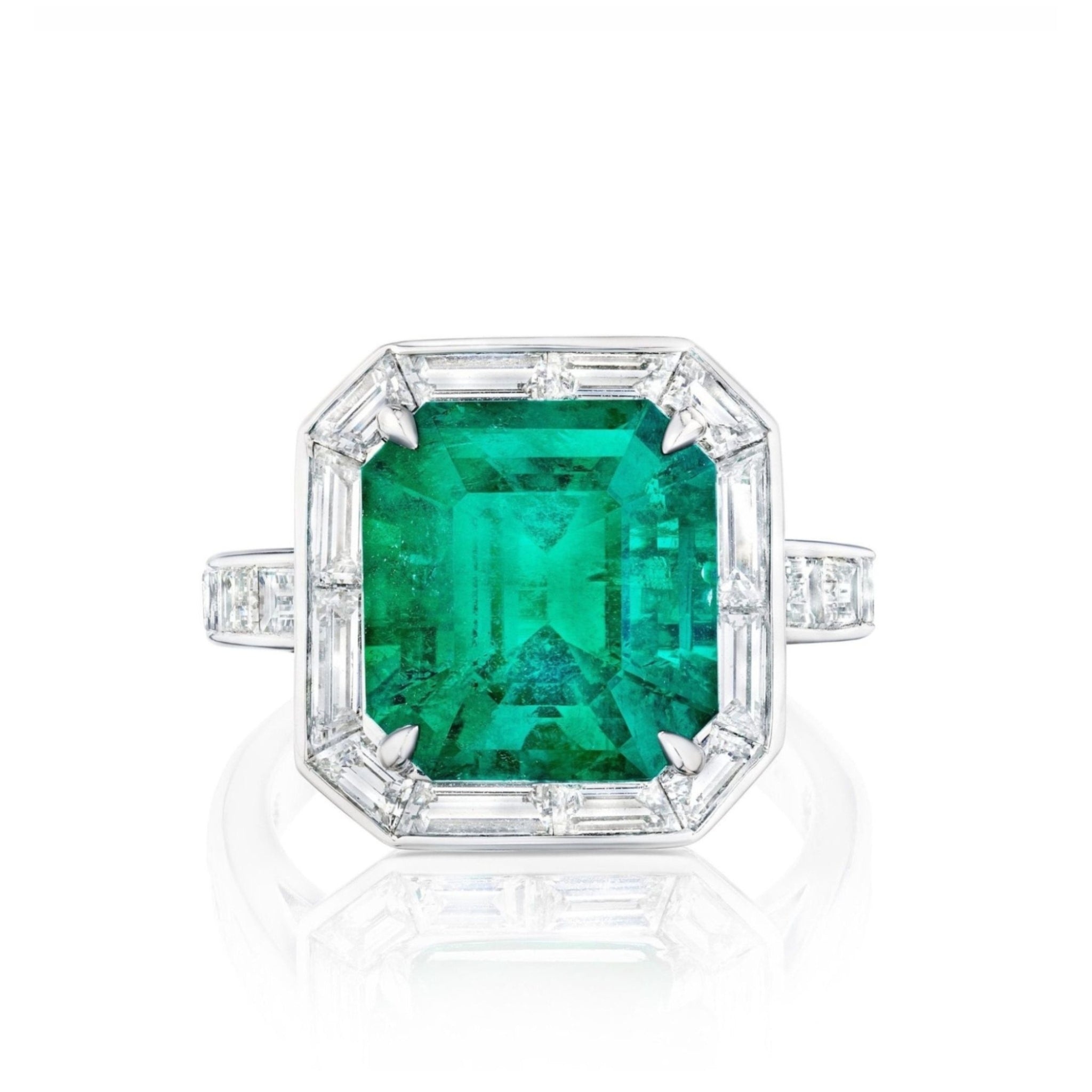 The Mosaic Asscher Cut Emerald and Baguette Diamond Cocktail Ring in Platinum features a striking asscher cut emerald centerpiece, set in a platinum band and accented with rectangular and baguette diamonds around the stone and partially down the band.