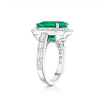 Introducing the Mosaic Asscher Cut Emerald and Baguette Diamond Cocktail Ring in Platinum, showcasing a striking asscher cut emerald at its center, beautifully accented by sparkling baguette diamonds along the band and encircling the main stone, all set against a white background.