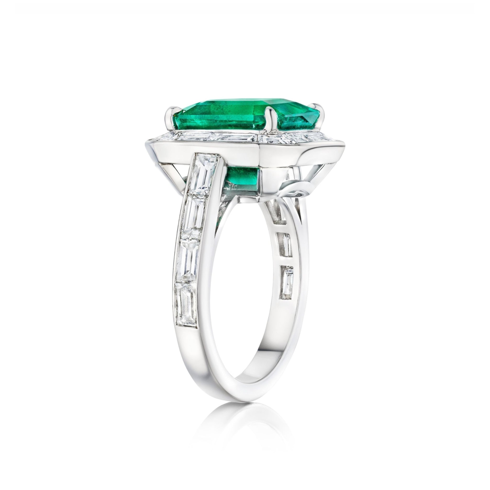 Introducing the Mosaic Asscher Cut Emerald and Baguette Diamond Cocktail Ring in Platinum, showcasing a striking asscher cut emerald at its center, beautifully accented by sparkling baguette diamonds along the band and encircling the main stone, all set against a white background.
