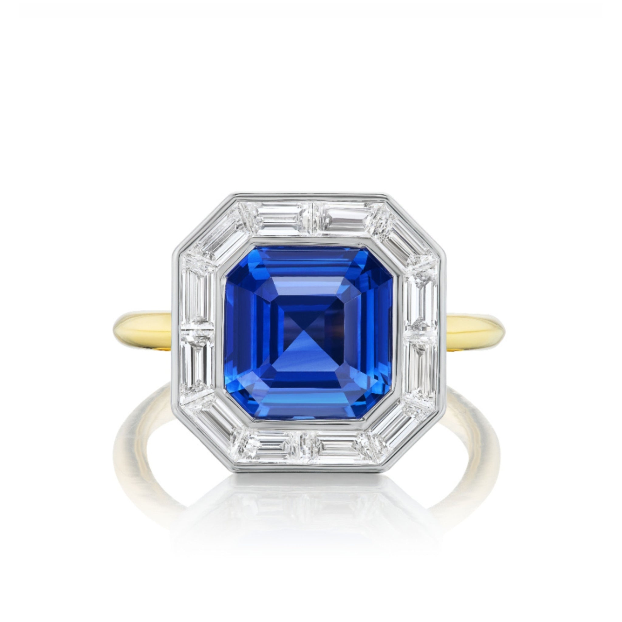 Introducing the Mosaic Ring with Asscher Cut Sapphire and Baguette Diamonds: a dazzling 18k gold piece showcasing a striking, Asscher cut blue sapphire at its center, surrounded by a brilliant halo of baguette diamond accents set in contrasting white metal.