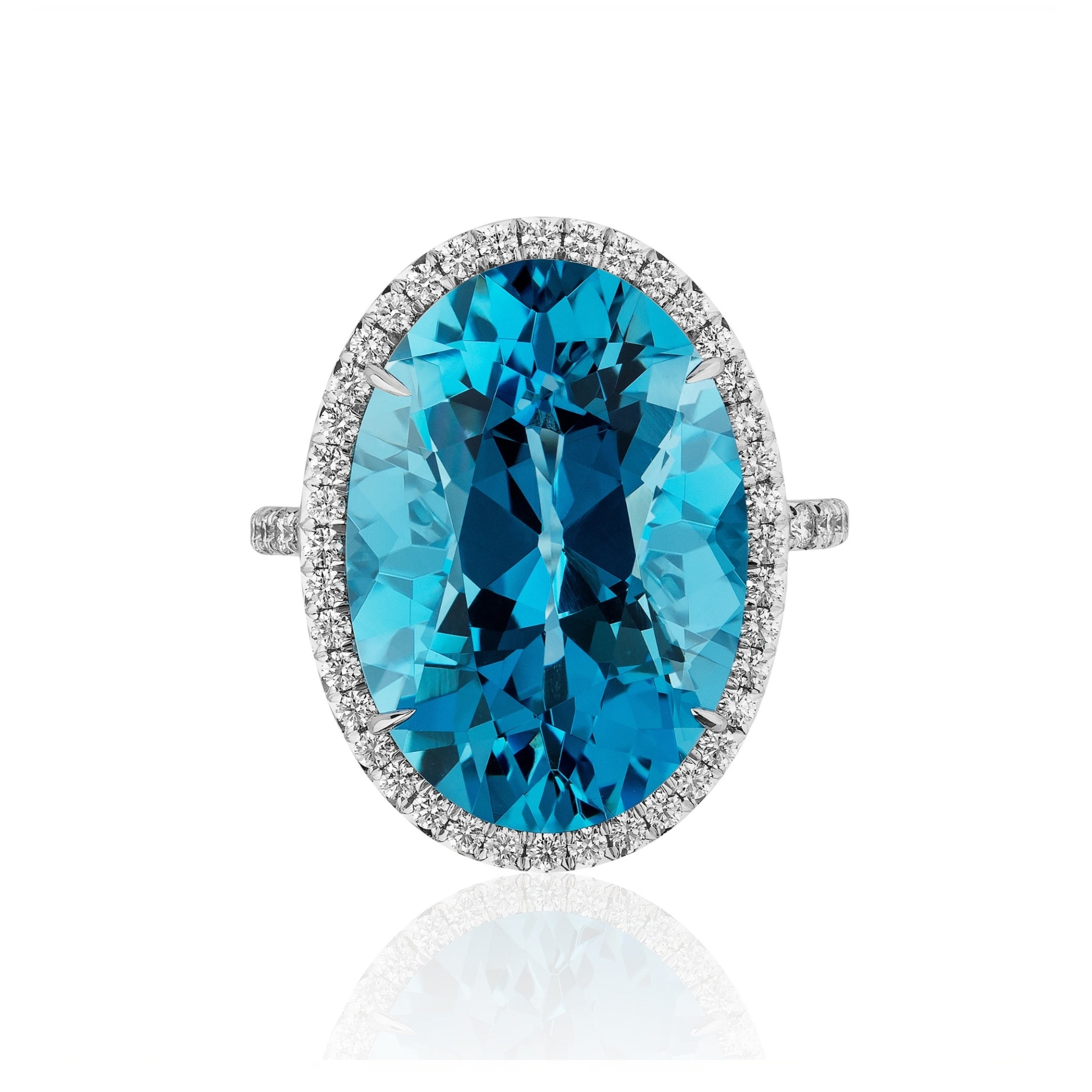 The Oval Blue Topaz Ring with Diamond Halo and Pavé Band, featuring an oval-cut blue topaz centerpiece surrounded by a halo of round diamonds and set in 18k white gold, is displayed on a white background.