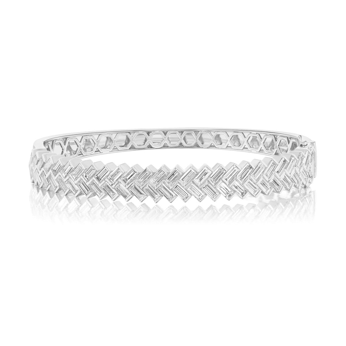The Chevron Baguette Diamond Bangle in White Gold is an 18k bracelet featuring a geometric zigzag pattern with rectangular segments, displayed on a white background with a subtle reflection.