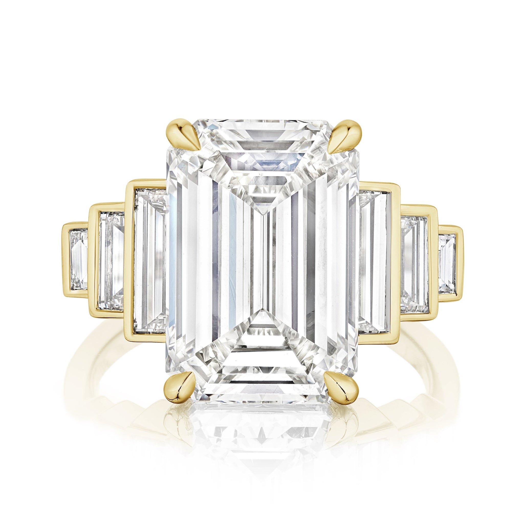 The Triple Echo Emerald Cut Diamond Engagement Ring features a large emerald cut center stone and bezel set baguette side stones in 18k gold. Its sleek, polished band perfectly highlights the brilliance of the diamonds.