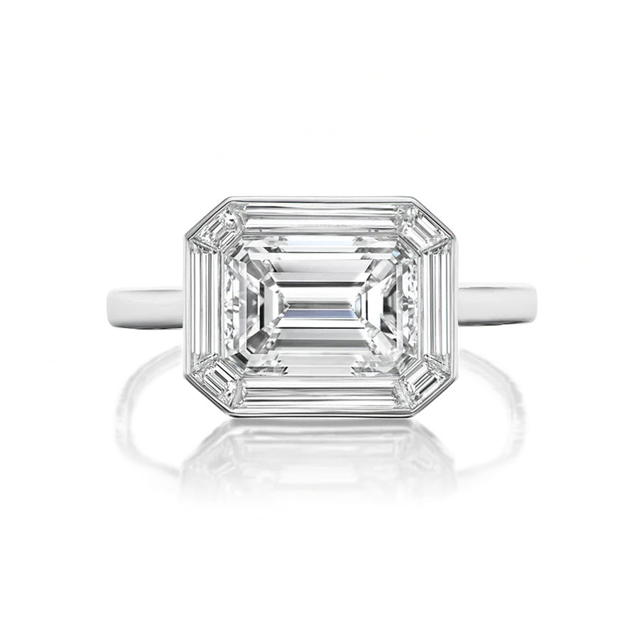 The East-West Set Mosaic Diamond Engagement Ring features an emerald-cut diamond with a baguette halo, set in polished white gold and displayed against a white background.