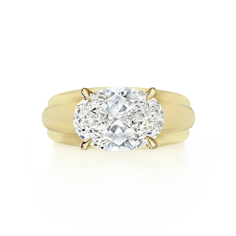 The East-West Set Oval Diamond Ribbed Engagement Ring in Yellow Gold features a wide ribbed band and an east-west set oval diamond in four prongs, showcased on a white background.