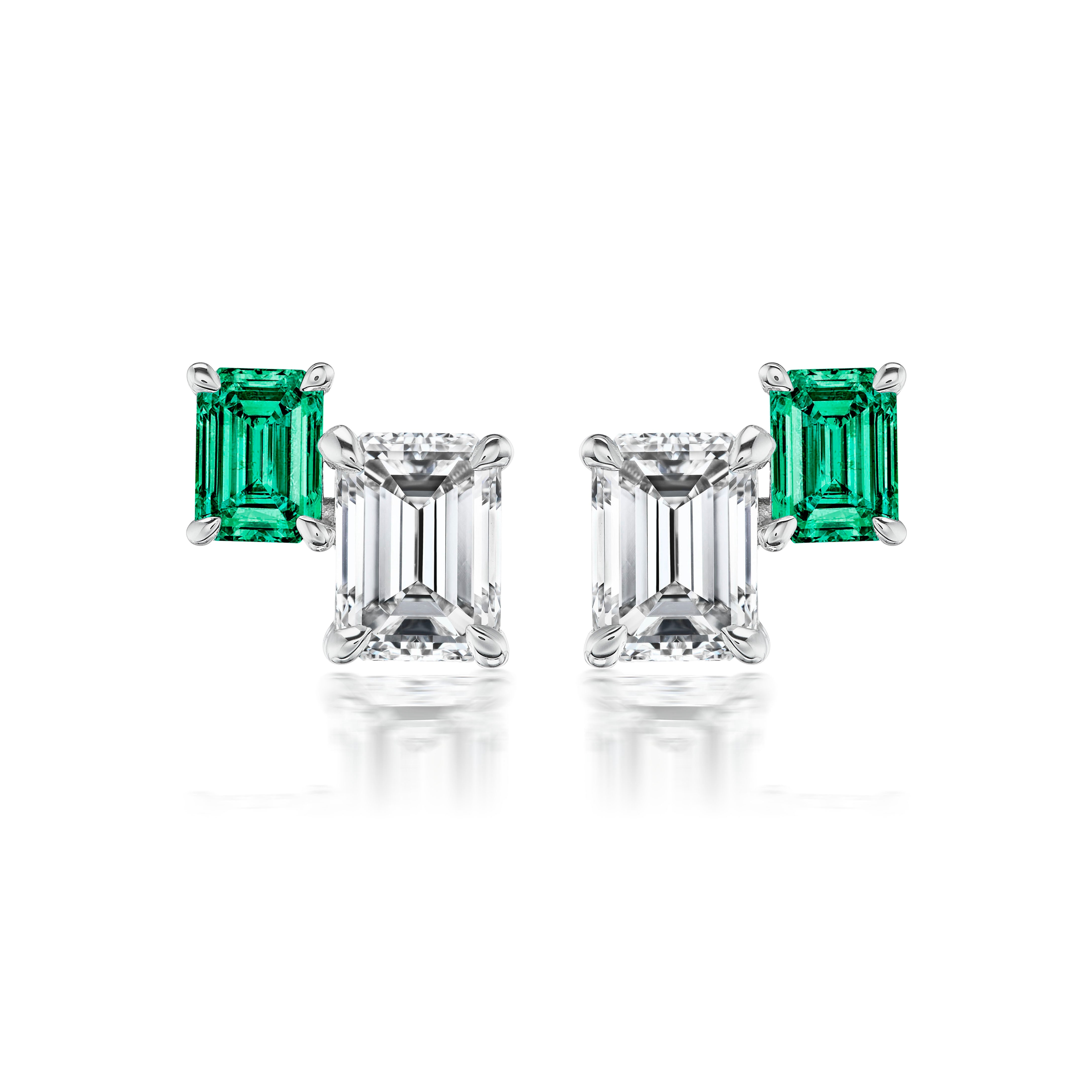 The Duo Studs in White Gold feature rectangular emerald cut emeralds above larger emerald cut diamonds, set in 18K white gold prongs and displayed against a white background.