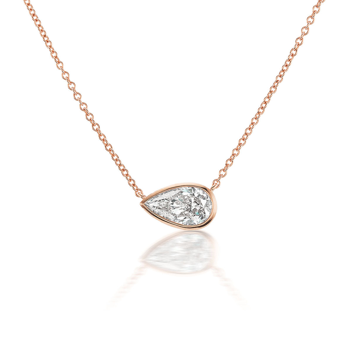 The Small East-West Bezel Set Pear Diamond Pendant in Rose Gold features a minimalist design with a delicate 18K rose gold bezel and pear diamond, displayed against a white background.