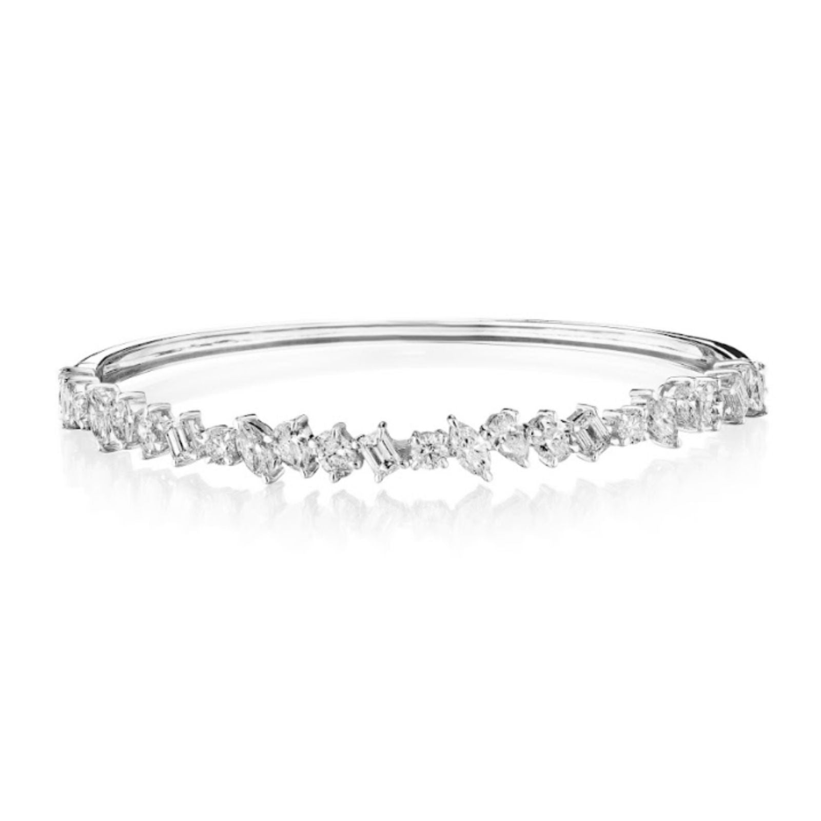 The Marching Mixed Shape Diamond Bangle features a silver motif and displays a row of baguette and round-cut white gemstones set in a clustered, irregular pattern across the top.