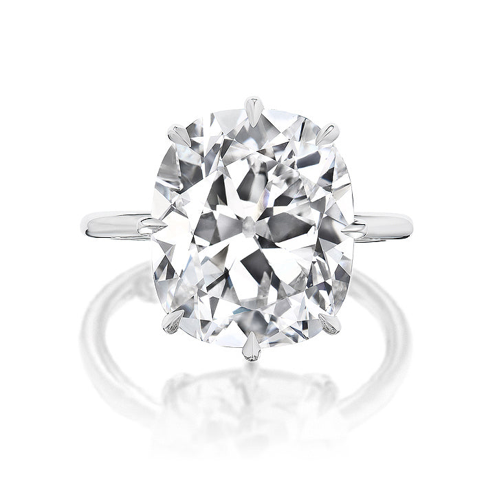 A close-up of the Antique Cushion Cut Diamond Solitaire Engagement Ring showcases a large cushion-cut diamond in four prongs on a simple silver band, set against a white background.