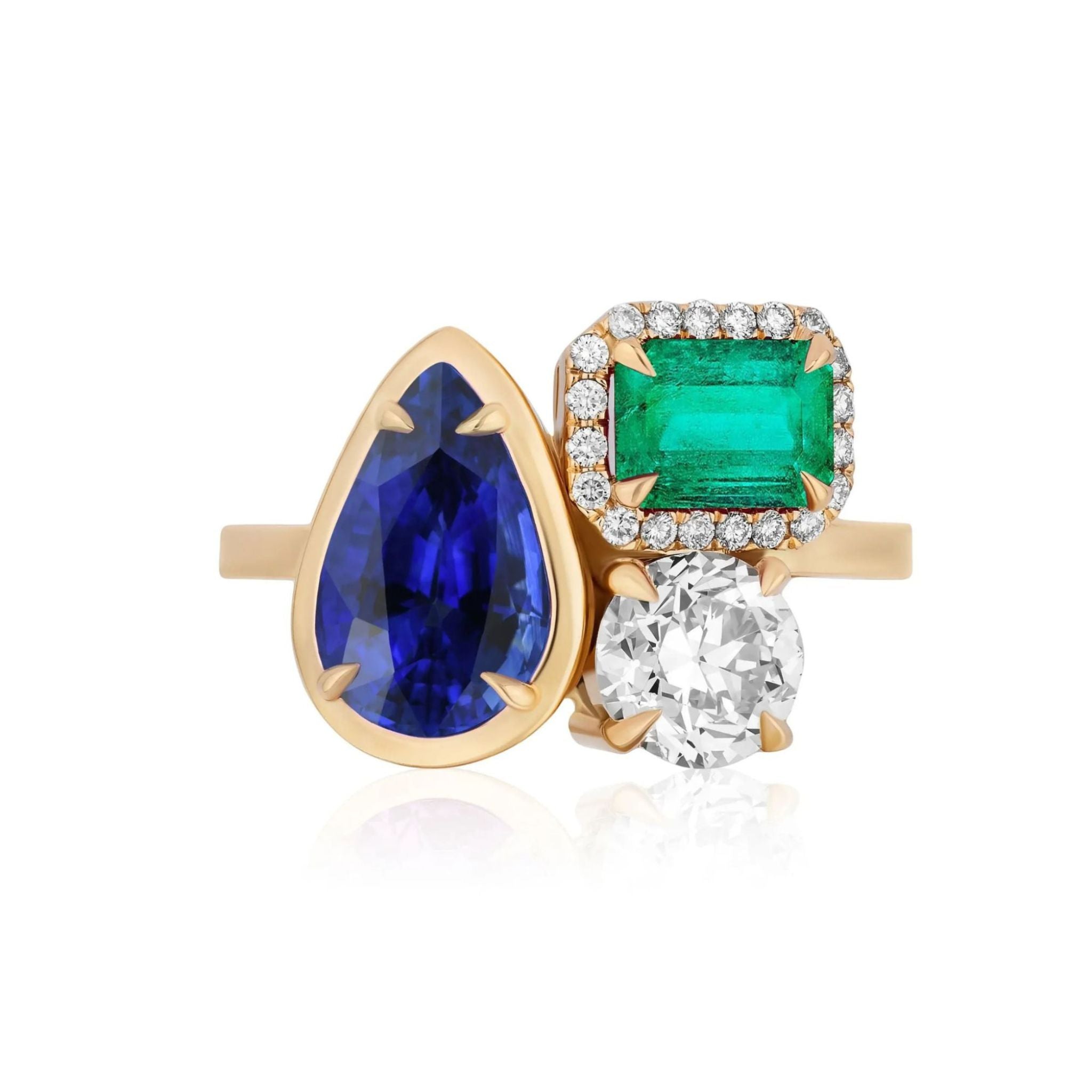 Introducing the Cluster Ring in Yellow Gold, showcasing a stunning arrangement of meticulously collet set gemstones: a pear-shaped blue sapphire, an emerald-cut green emerald surrounded by pavé-set diamonds, and a sparkling round diamond—all artfully set side by side.