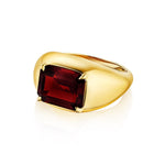 An elegant Bombé Ring in 18k yellow gold featuring an east-west set emerald cut ruby, displayed against a white background.