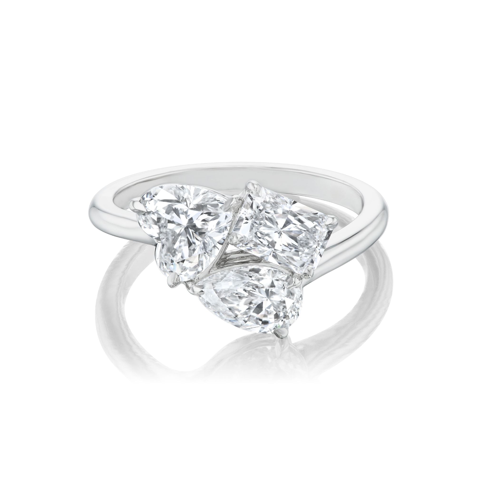 A stunning three-stone ring in white gold featuring a radiant cut diamond, a heart-shaped diamond, and a pear-shaped diamond, all set closely together in an elegant design.