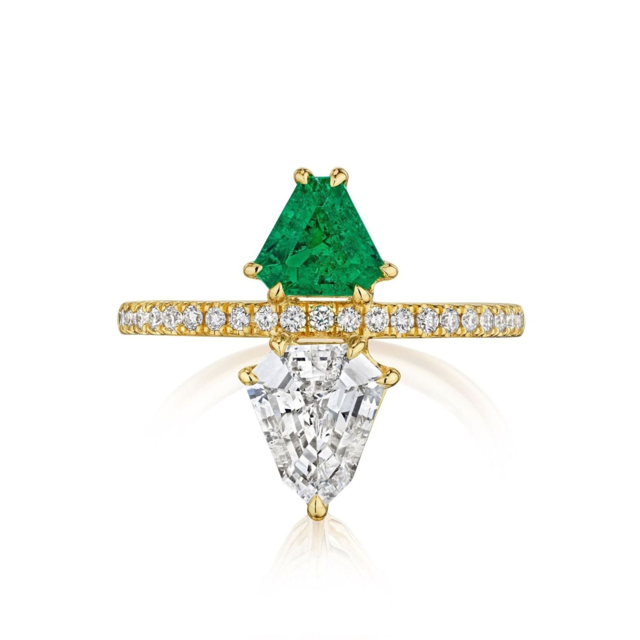 The Emerald and Diamond Double Shield Ring in Yellow Gold showcases a vibrant shield-cut emerald and an inverted triangular shield-cut diamond as its focal stones, set in 18k yellow gold with a row of small diamonds adorning the band.