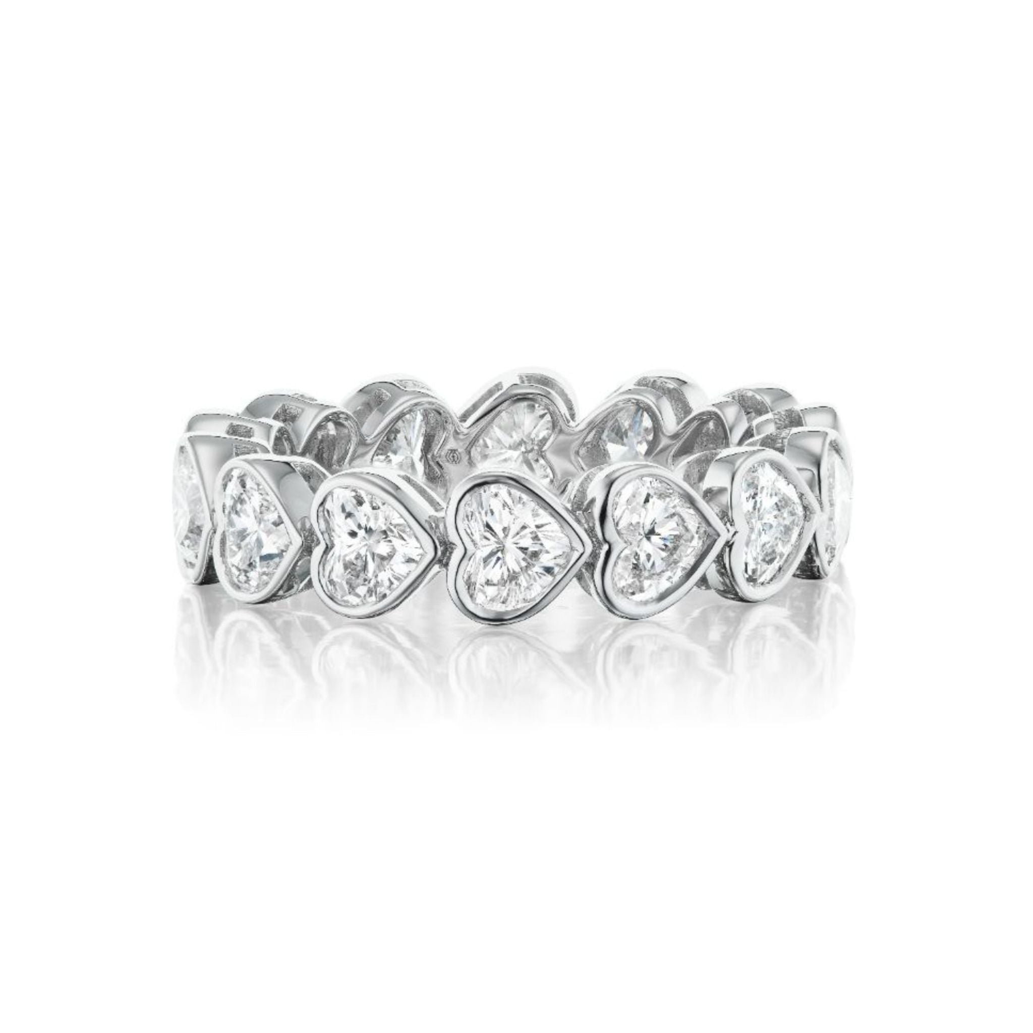 Introducing the Chasing Hearts Bezel Set Eternity Band, a silver ring adorned with a continuous pattern of heart-shaped settings, each embellished with a clear, sparkling gemstone of VS1-VS2 clarity, beautifully showcased on a white background.