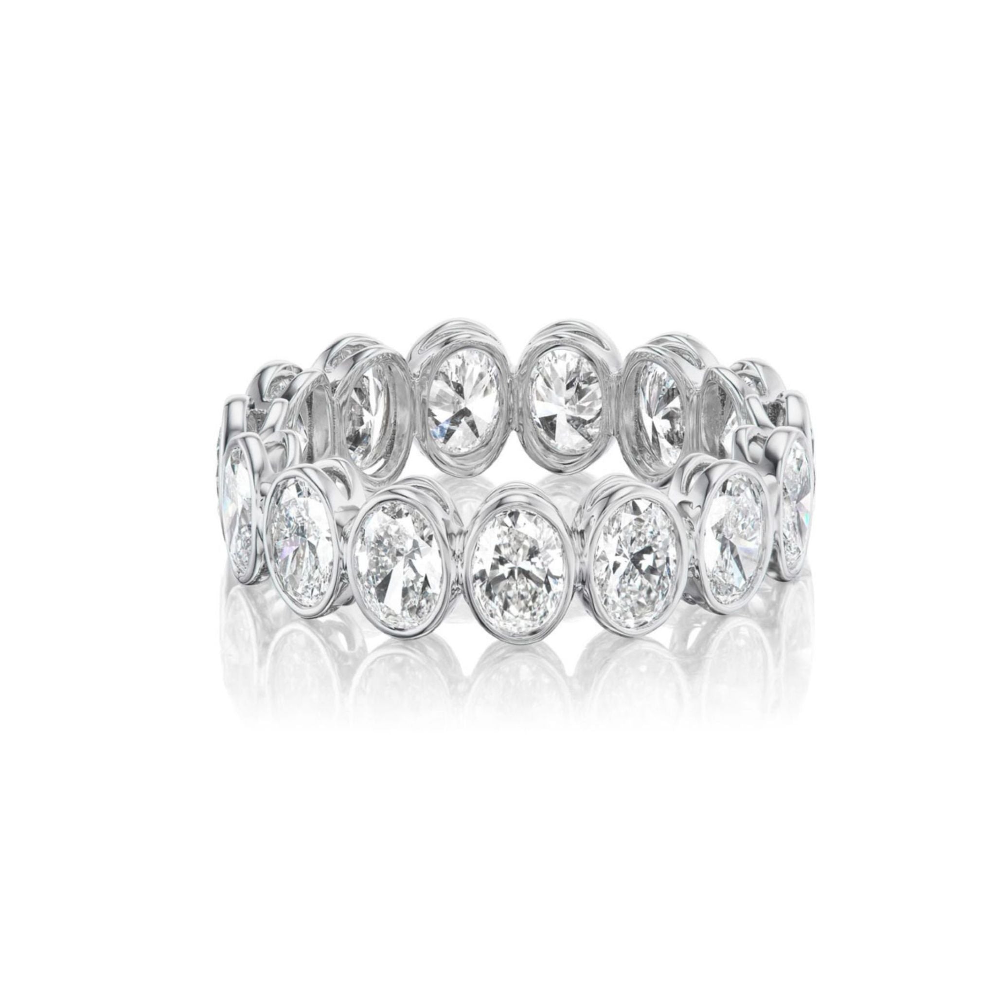 The Oval Bezel Set Diamond Eternity Band in White Gold features sparkling oval diamonds bezel-set all the way around, elegantly showcased against a white background.